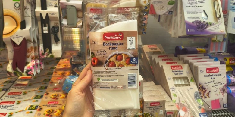 Rukou držená balení pečicího papíru v obchodě s kuchyňskými potřebami.