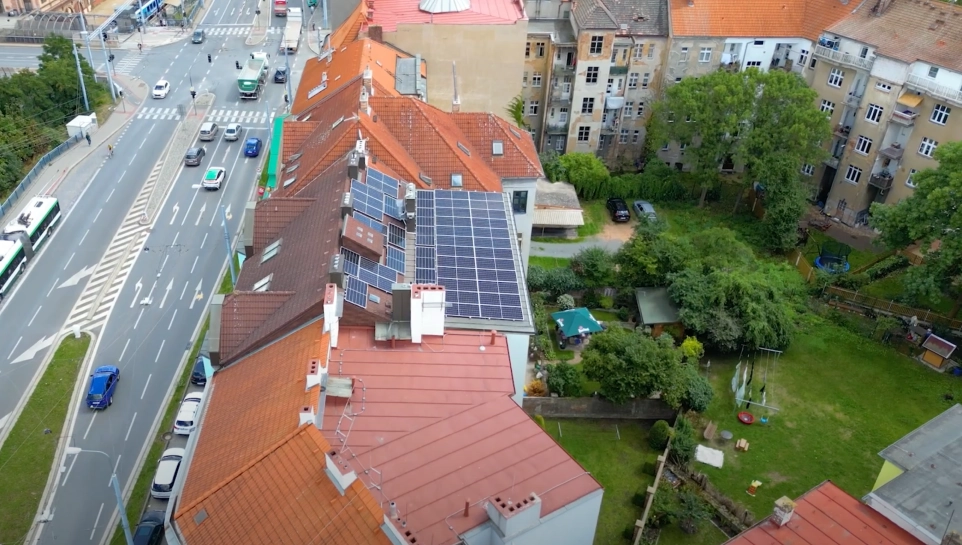 Fotovoltaické panely na střechách bytového domu v městské zástavbě.