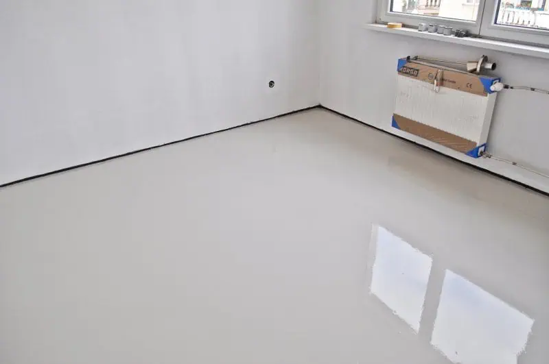 Běle stěrka nivelační na podlaze po aplikaci s leskem.