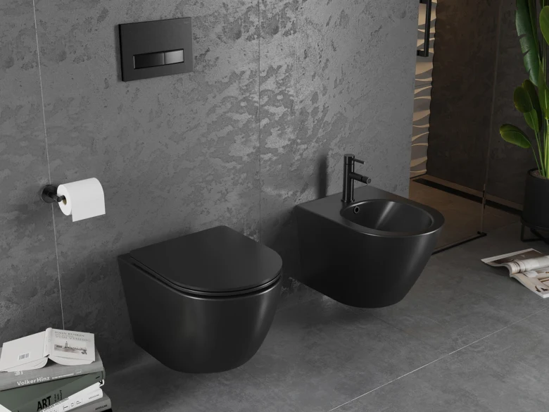 Černý bidet nainstalovaný vedle zdi s WC v šedé koupelně.