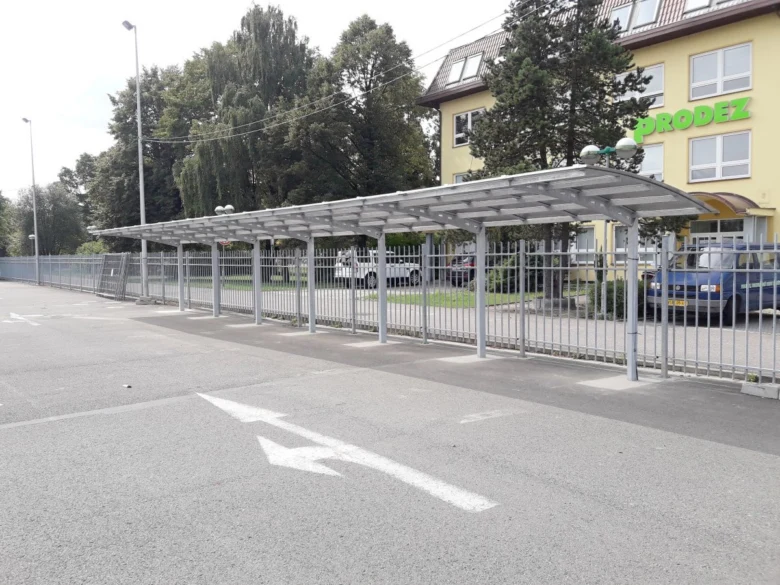 Nový přístřešek pro auta postavený svépomocí za plotem.