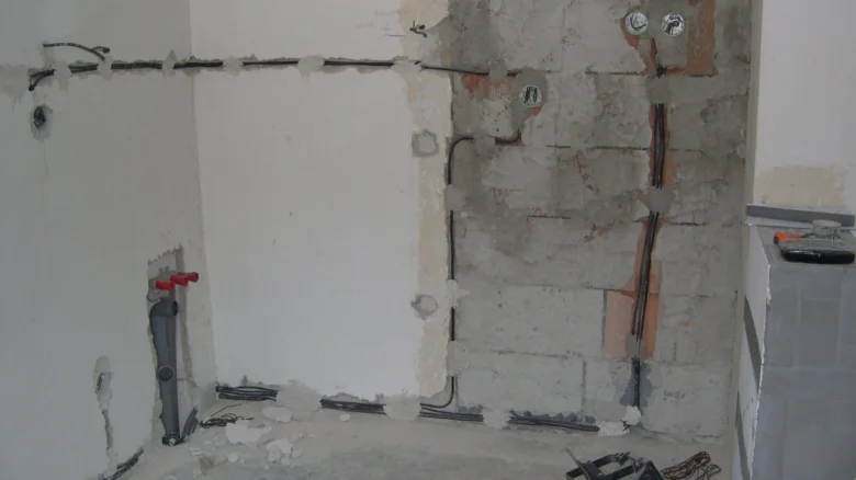 Fotografie koupelny v rekonstrukci s viditelnými instalacemi.