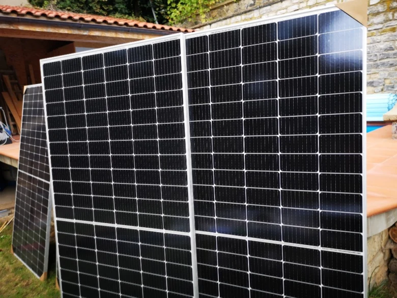 Dvě velké fotovoltaické panely stojící venku u kamenné budovy.