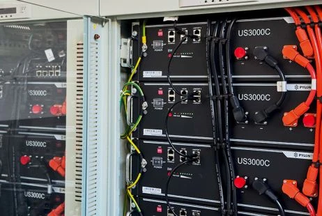 Černé baterie pro solární elektrárnu s oranžovými kabely.