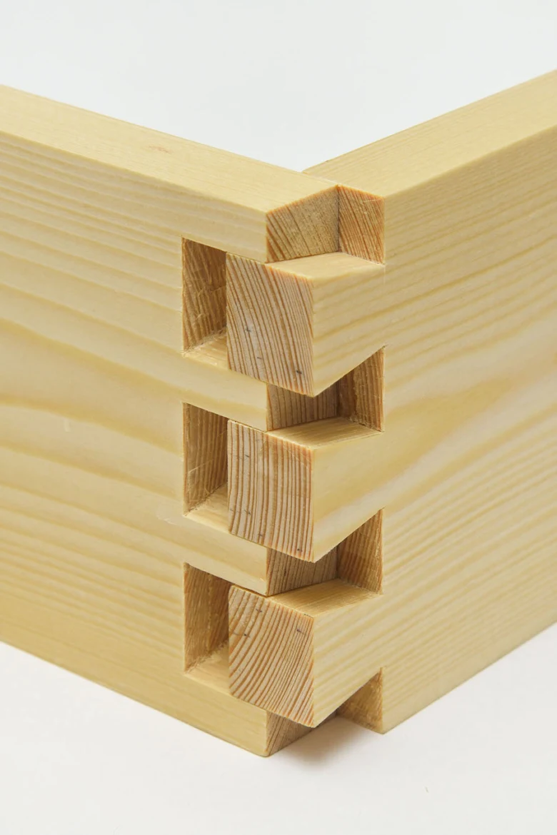 Detail dřevěného spojení čep-dlab v rohu konstrukce.