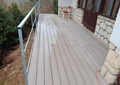Dřevěná terasa ve svahu s ohradami u domu.