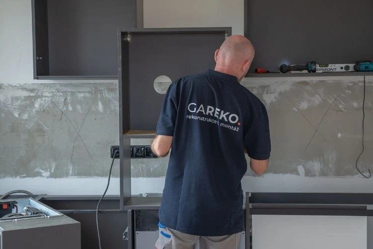 Montáž kuchyně na míru: dělník instaluje skříňovou konstrukci.