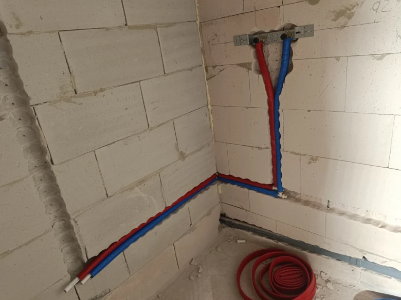 Instalace plastových vodovodních trubek v koutě zdiva.