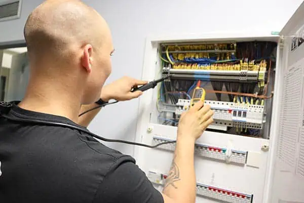 Elektrikář testuje rozvaděč v Praze multimetrem.