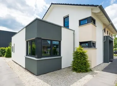 Moderní dům s bílou fasádou a tmavě šedými okny.