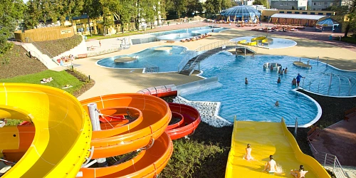 Venkovní akvapark s barevnými vodními skluzavkami a bazény.