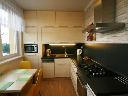 Moderní dřevěná kuchyně s černými pracovními deskami.