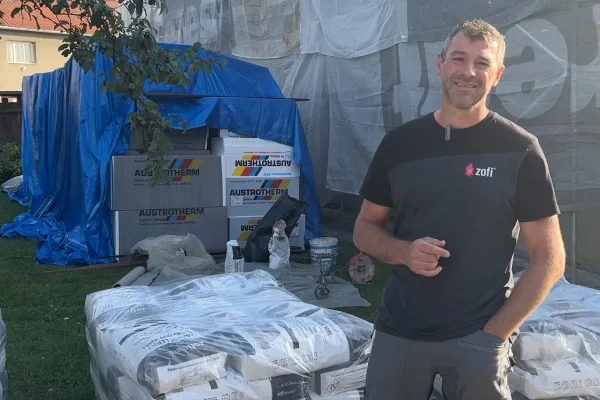 Muž stojí vedle polystyrenových desek a izolačních materiálů pro fasádu.