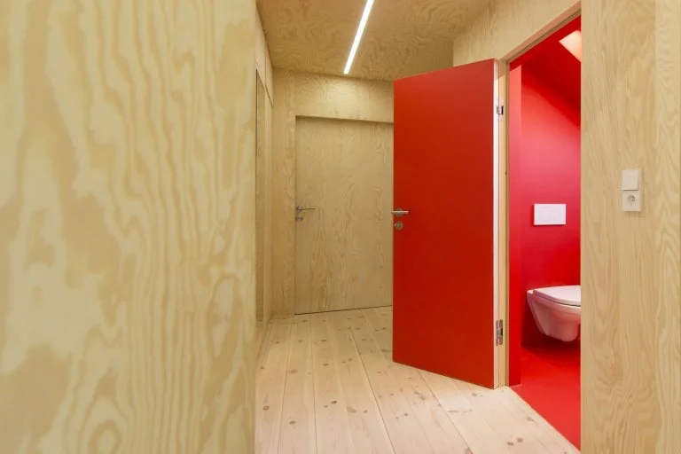 Moderní dřevěný chodba s červenou dveřmi do toalety