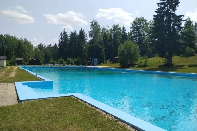 Venkovní plavecký bazén v Chrastavě obklopený lesy.