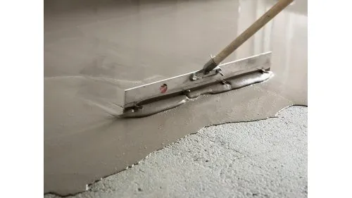 Nástroj na vyrovnávání samonivelační stěrky se rozlévá po podlaze.