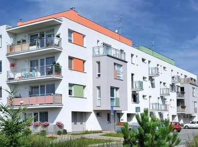 Moderní bytový dům s barevnými fasádami v bílé, oranžové a zelené.