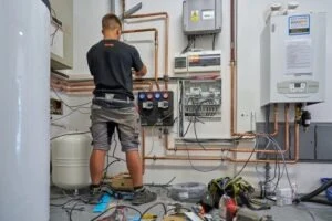 Montáž plynového kotle s měděnými potrubími v nehotové místnosti.