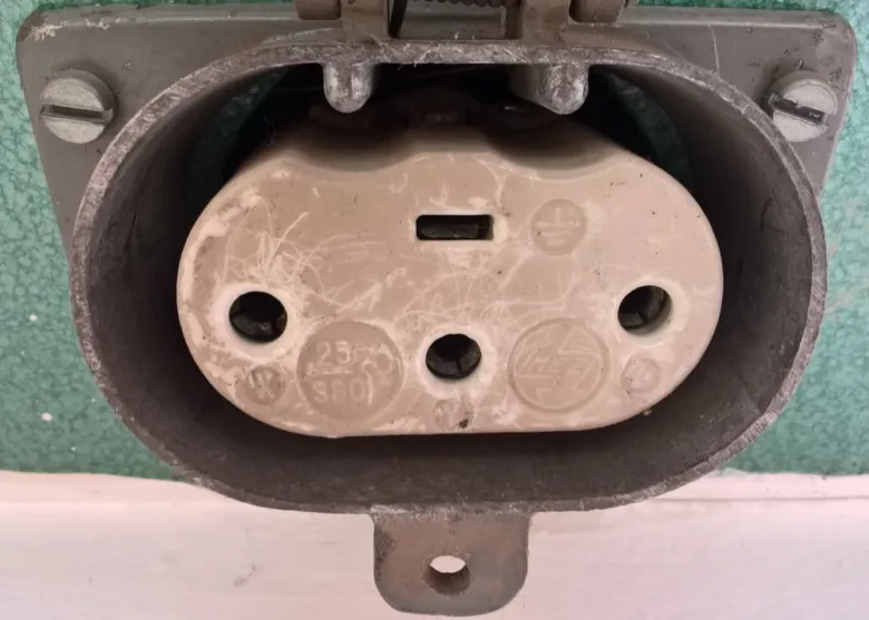 Přepážka zásuvky pro domácí elektroinstalaci s viditelnými kontakty.