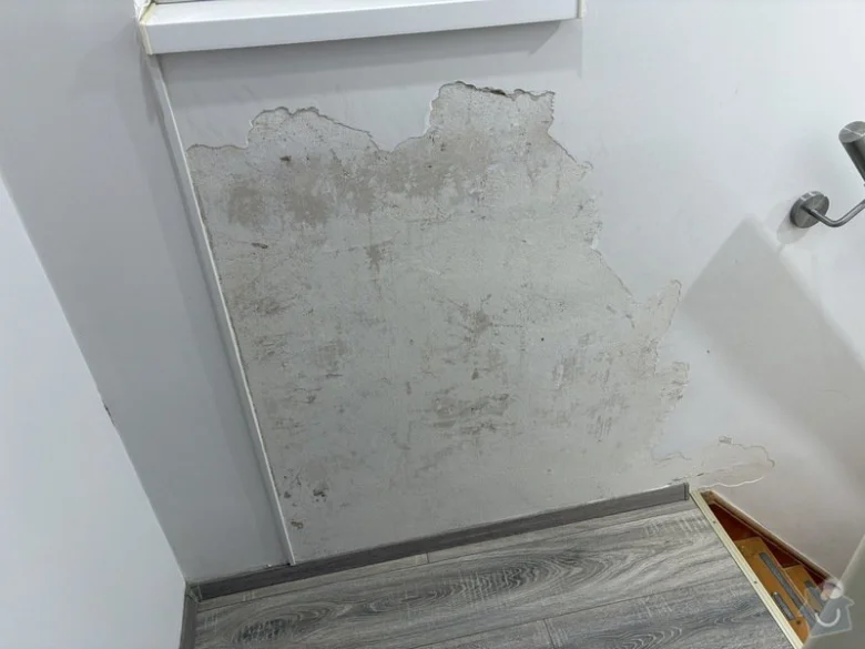 Poškozená omítka na stěně potřebuje opravu zedníkem.