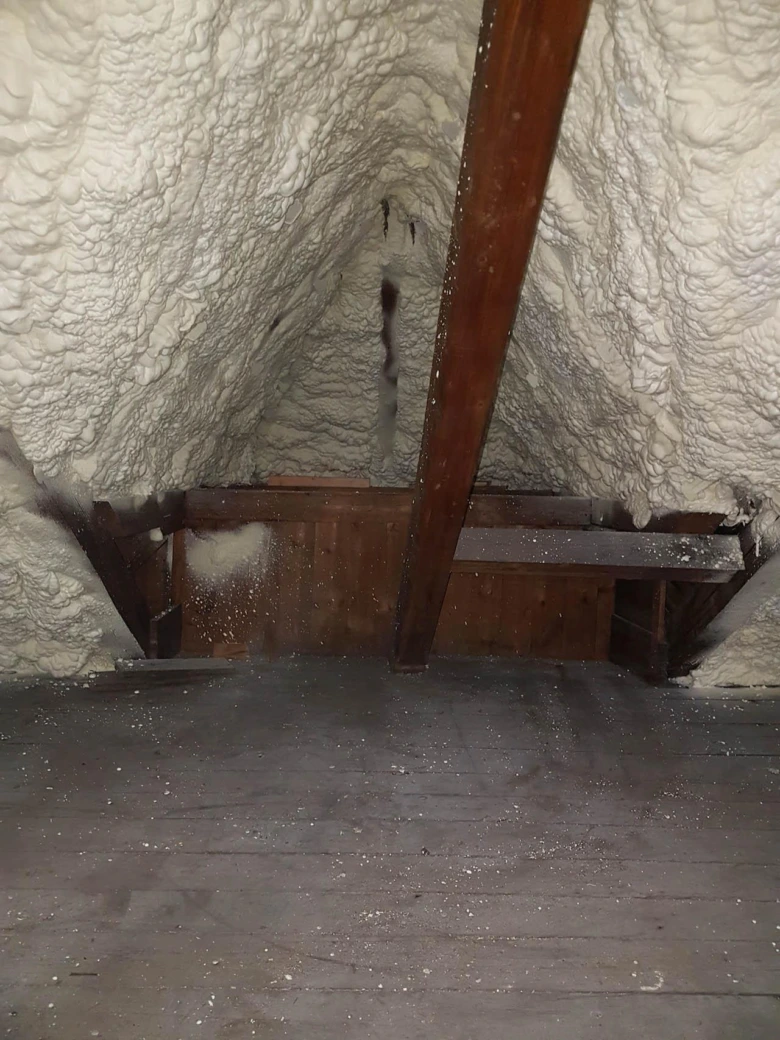 Podkroví zateplené pěnovou izolací s dřevěnými trámy.