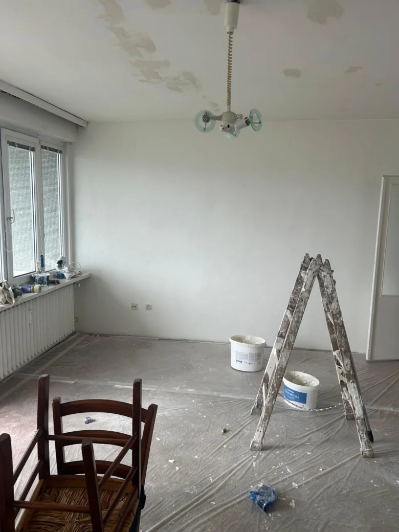 Pracovní prostor při malování bytu v Praze s leštěnou stěnou a nástroji.